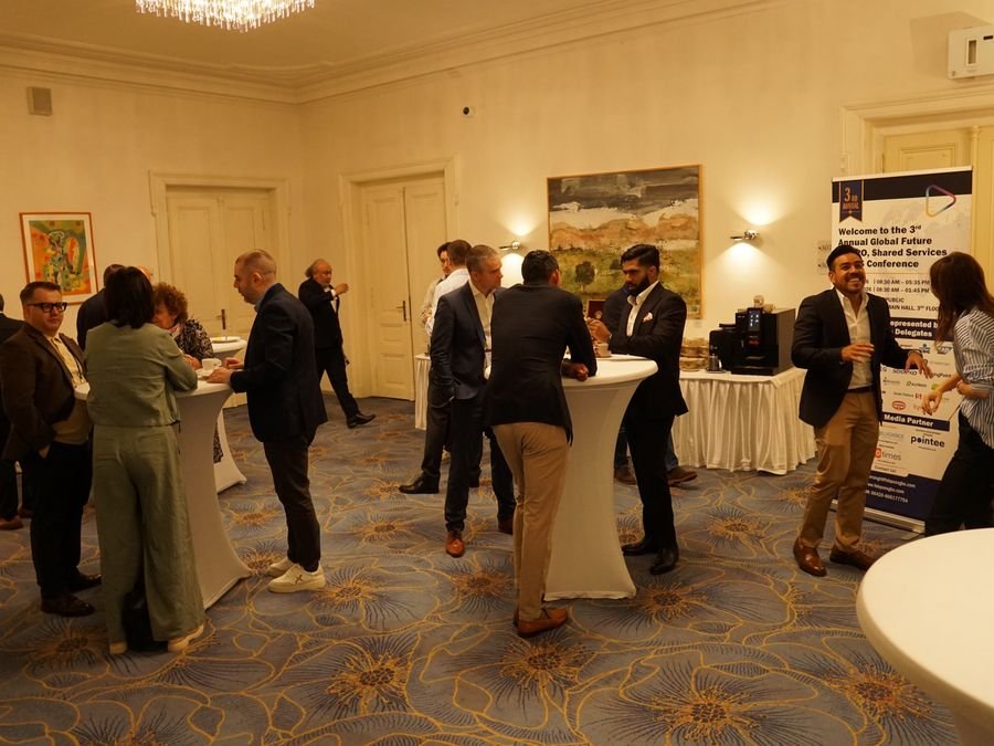 Networking in the break room by the welcome banner at Hotel KINGS COURT, Prague, 2026 edition of the Global Future of BPO, Shared Services & GBS Conference